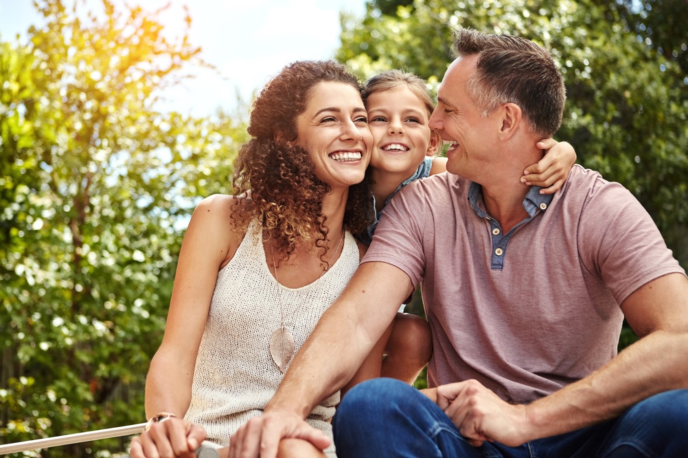 A family smiling together outdoors.